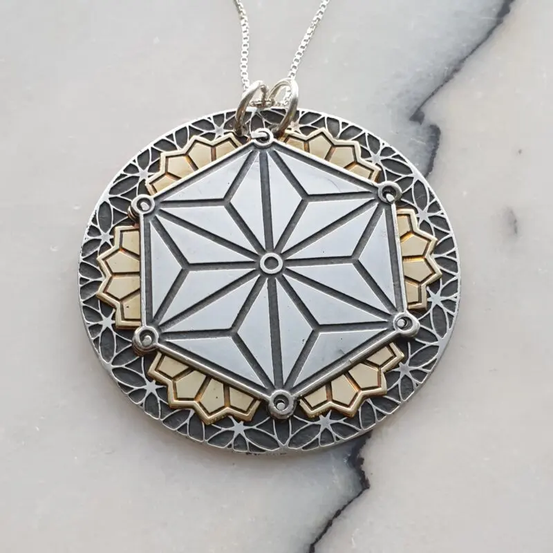 Alchemy in Art. Handcrafted pendant featuring sacred geometry designs, crafted from etched silver and brass layers joined with silver cold connections.