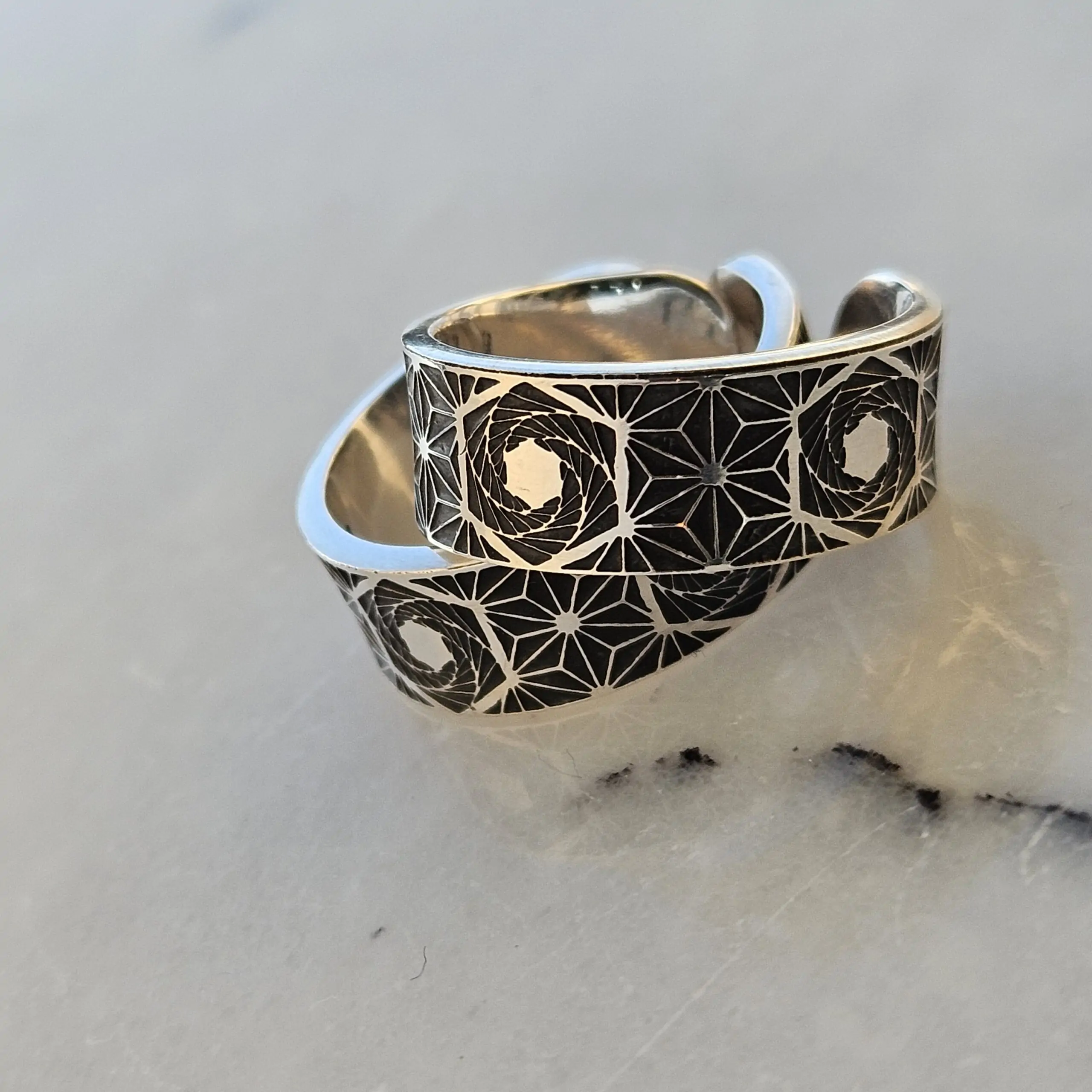 a pair of sterling silver wedding rings, etched with sacred geometry patterns
